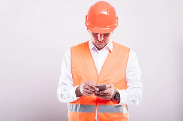 Foreman usando chaleco reflectante navegando o enviando mensajes de texto en smartphon —  Fotos de Stock