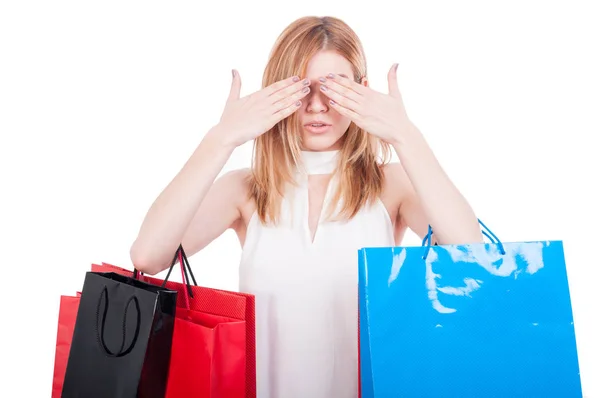 Woman holding shopping bags and covering her eyes