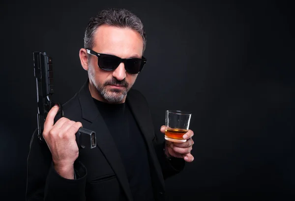 Вооруженный стрелок со стаканом алкоголя — стоковое фото