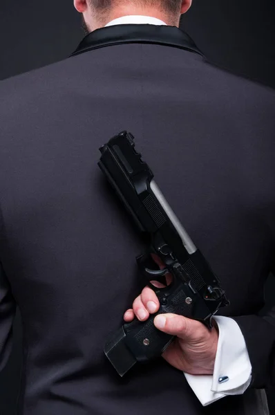 Criminele gangster holding revolver op zijn rug — Stockfoto