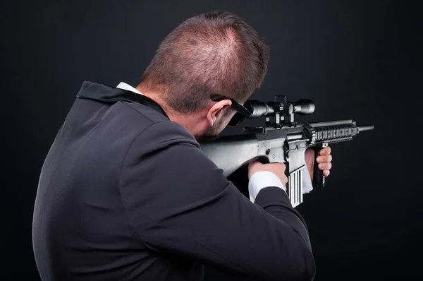 Back view of violent mafia member aiming rifle