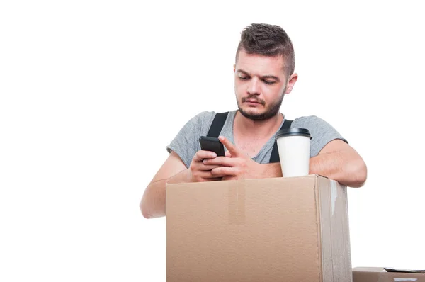 Mover man texting and having coffee on boxes — Stock Photo, Image