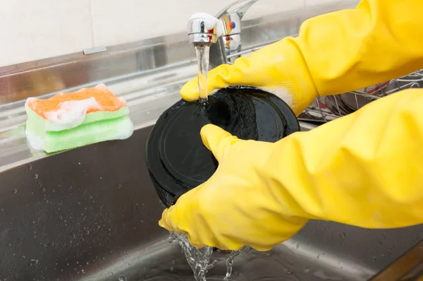 Householder hand rinsing the dishes in the sink — Stock Photo, Image