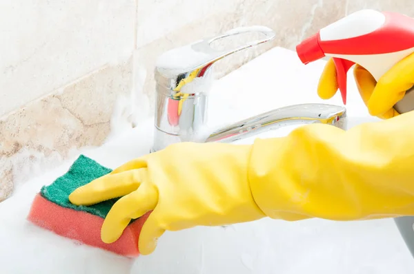 Pembantu rumah tangga sedang membersihkan wastafel kamar mandi dalam close-up — Stok Foto