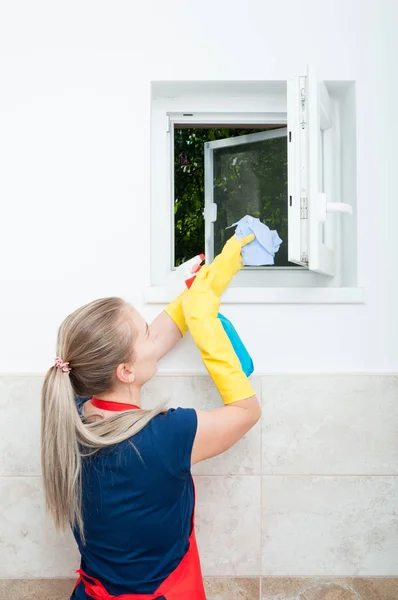 Jeune femme au foyer essuyant la fenêtre — Photo