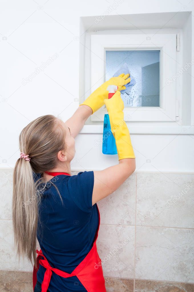 Woman wiping the bath window with cleaning spray