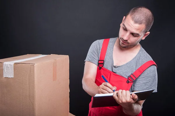 Mover cara olhando para caixas escrevendo na agenda — Fotografia de Stock