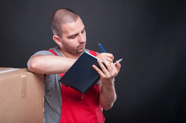 Mover guy writing in agenda with boxes around — Stock Photo, Image