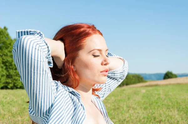 Mulher ruiva bonita relaxante ao ar livre em tempo ensolarado — Fotografia de Stock