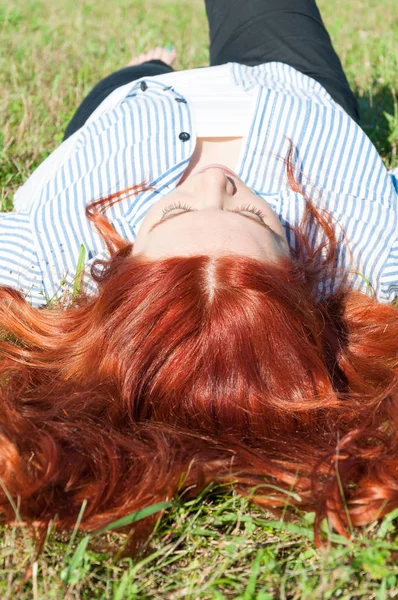 Relajada pelirroja chica acostada en la hierba — Foto de Stock