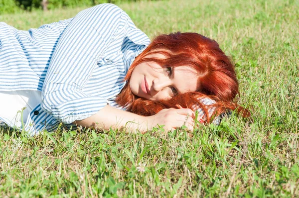 Belle femme aux cheveux rouges couchée sur l'herbe outdoos — Photo