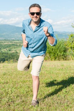 Neşeli hipster adam güneşli çayır üzerinde çalışan