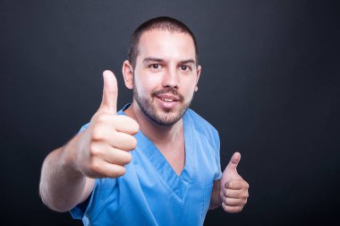 Gülümseyen erkek tıbbi hemşire başparmak gösterilmesini