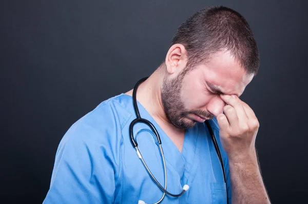 Joven doctor vistiendo uniformes con dolor de cabeza —  Fotos de Stock