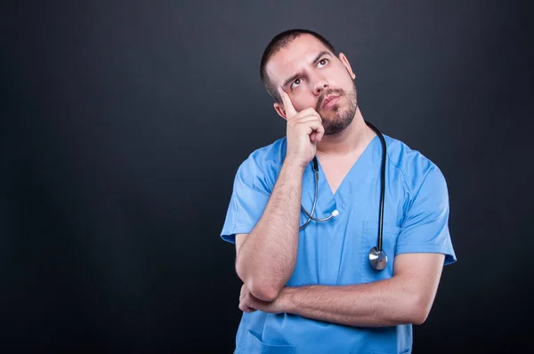 Portrait of doctor wearing scrubs with stethoscope thinking — Stock Photo, Image