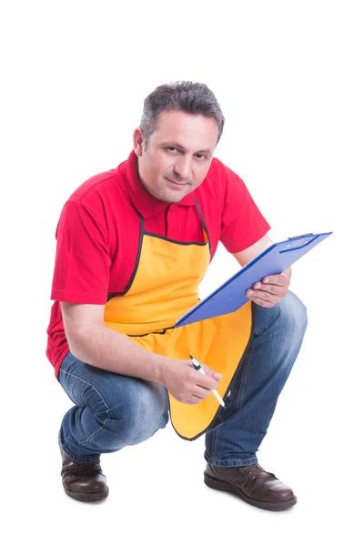 Handsome hypermarket employee writing on clipboard — Stock Photo, Image