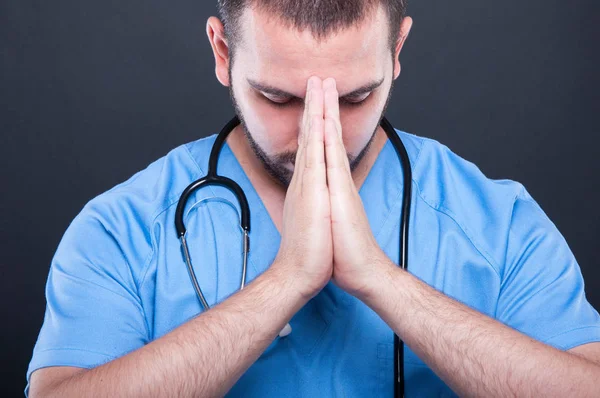 Médico de cerca vistiendo uniformes con estetoscopio rezando —  Fotos de Stock