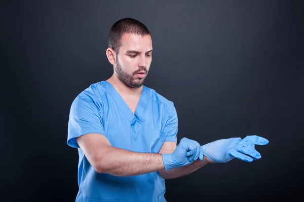 Doctor with scrubs putting on his latex gloves — Stock Photo, Image