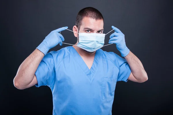 Läkare med scrubs att sätta på sin sterila mask — Stockfoto