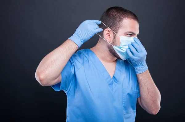 Вид збоку лікар одягає свою стерильну маску — стокове фото