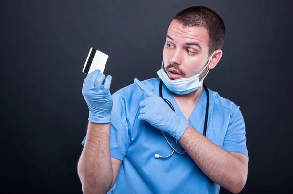 Doctor vistiendo uniformes y máscara apuntando tarjeta de crédito —  Fotos de Stock