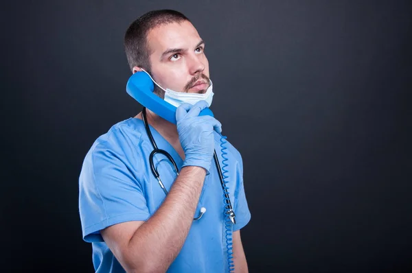 Doctor wearing scrubs holding telephone receiver — Stock Photo, Image
