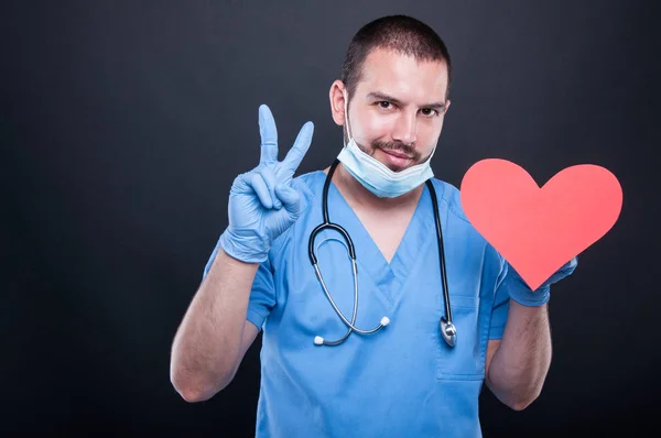 Cardiólogo con forma de corazón rojo mostrando paz —  Fotos de Stock