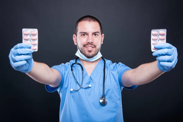 Läkare som bär scrubs visar två tabletter blister — Stockfoto