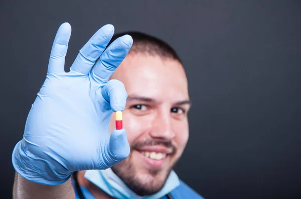 Вибірковий фокус лікаря, який носить скраби, тримаючи одну таблетку — стокове фото