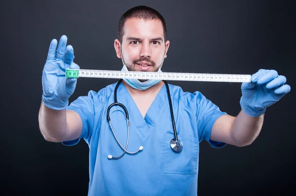 Plastikkirurg bär scrubs visar måttband — Stockfoto