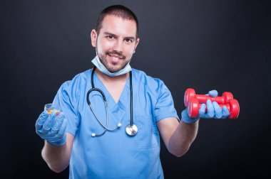 Plastik cerrah tutmak dumbbell ve hapları önlük giyiyor