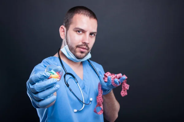 Läkaren håller piller framför måttband — Stockfoto