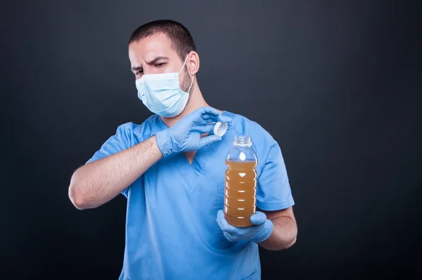 Медик в маске для лица держит плохо пахнущую воду — стоковое фото