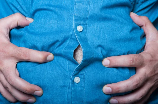 Man hold hands over his swollen abdomen — Stock Photo, Image