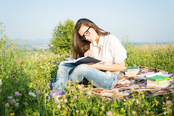 Mujer pone en el campo verde y lee libro — Foto de Stock