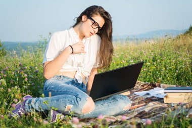 Genç kadın açık dizüstü bilgisayar ile çimenlerin üzerinde