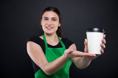 Mutlu genç satıcı tek kullanımlık bir kahve sunan