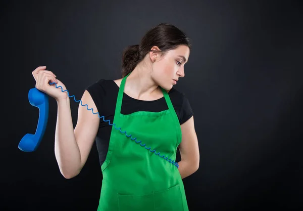 Bored supermarket clerk holding phone receiver — Stock Photo, Image