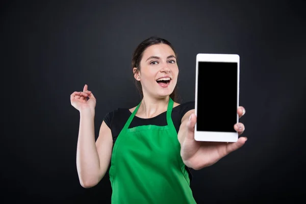 Smiling supermarket female employee showing smartphone — Stock Photo, Image
