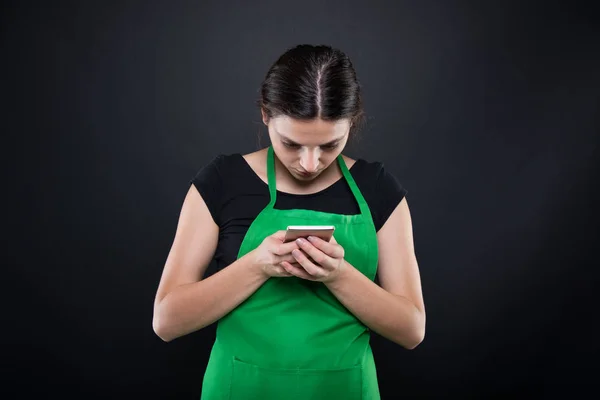 Young female seller texting a message on smartphone — Stock Photo, Image
