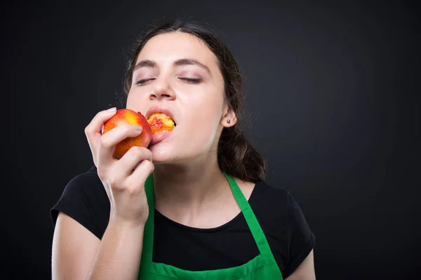 Портрет красивого служащего, с удовольствием поедающего нектарин — стоковое фото