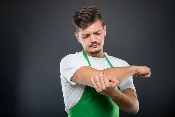 Portrait of supermarket employer holding elbow like hurting — Stock Photo, Image