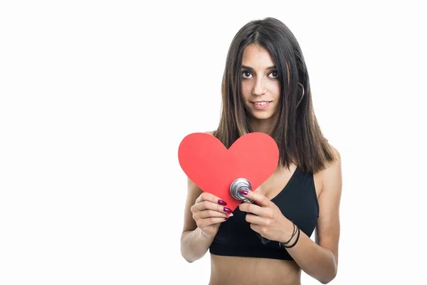 Fit girl holding red heart shape and stepthoscope — Stock Photo, Image