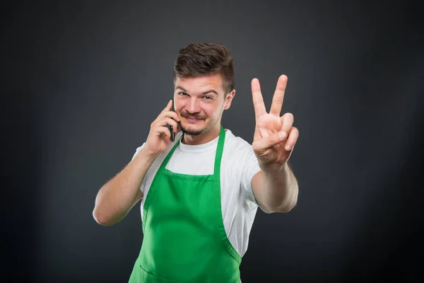 Supermercado empregador falando ao telefone mostrando gesto de paz — Fotografia de Stock