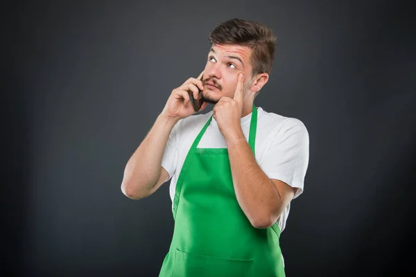 Supermarket pracodawca mówi o phone czyniąc gest myślenia — Zdjęcie stockowe