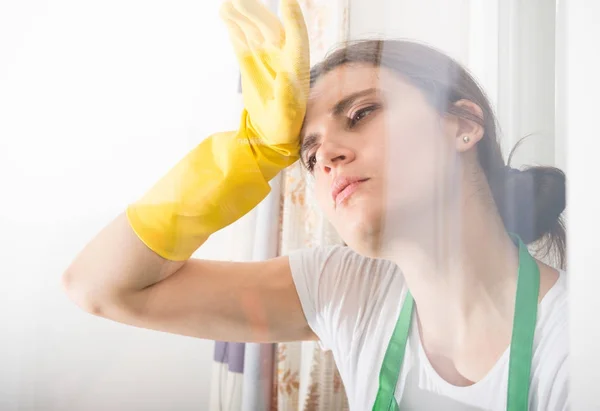 Mujer cansada con guantes protectores limpiándose la frente — Foto de Stock