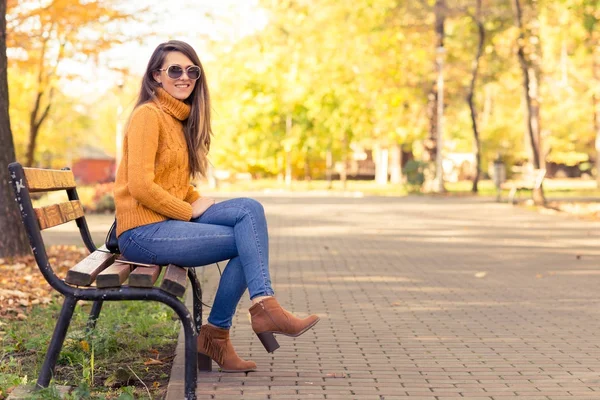 Jolie fille assise au banc dans le parc d'automne — Photo