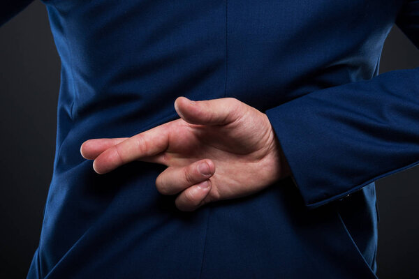 Closeup view of businessman standing with crossed fingers