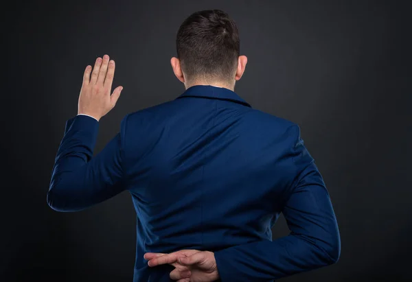 Человек в деловом костюме держит скрещенные пальцы — стоковое фото
