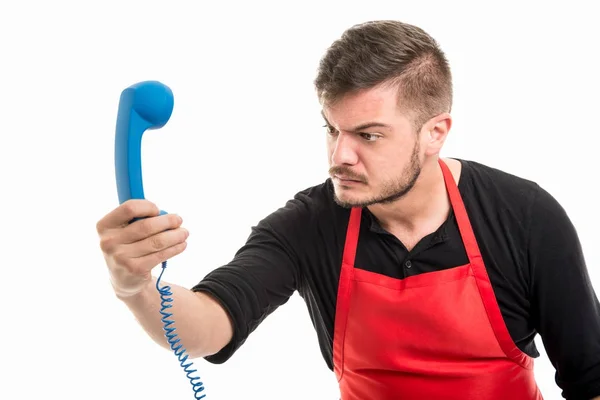 Hombre empleador de supermercado mirando enojado en azul receptor de teléfono —  Fotos de Stock